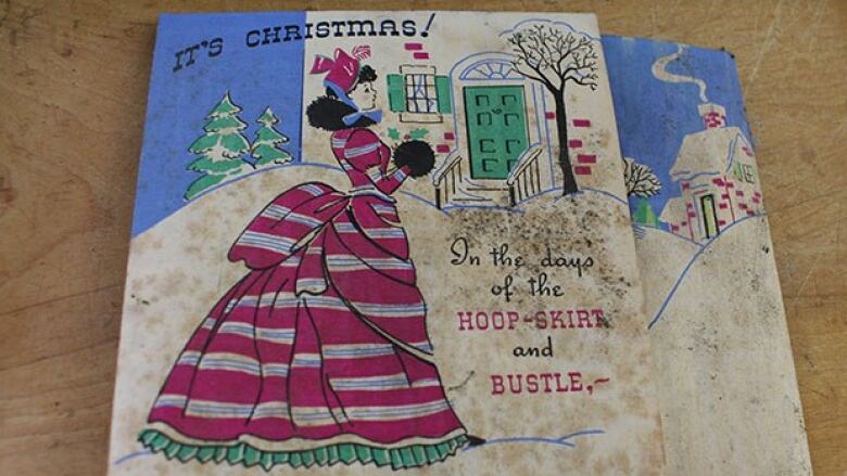 A Christmas card shows a woman in an old-fashioned dress and says 