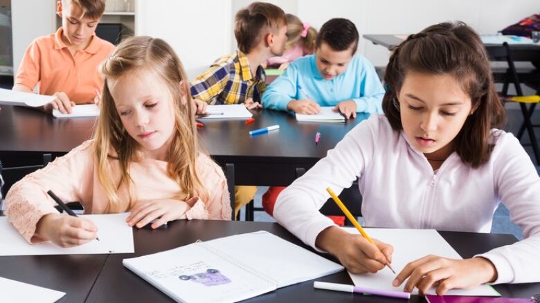 Teacher goes through classroom checking in with elementary-aged students.