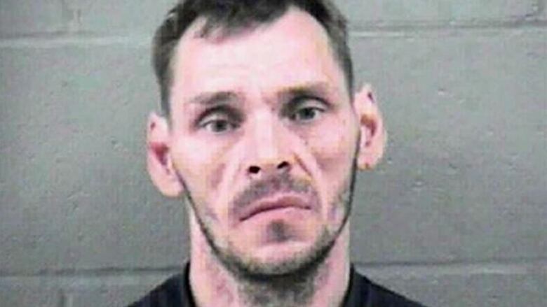 An earlier photo of Schoenborn from around the time of the child killings shows a man with a blank look and light beard standing in front of a grey wall.