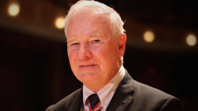 Smiling man with white hair and wearing suit and tie