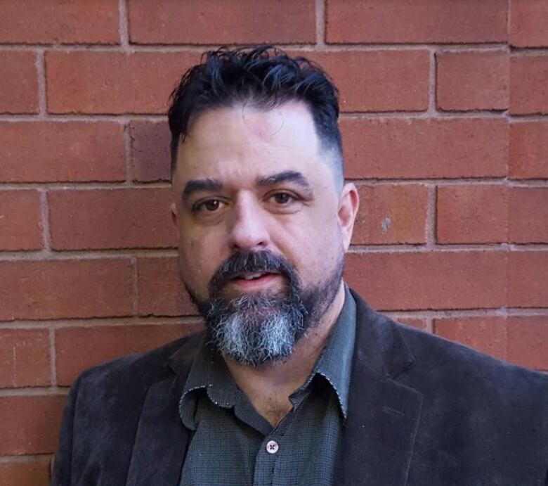 A man standing in front of a brick wall.