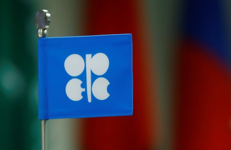 A small, blue paper flag on a wire stick with white letter-like symbols that spell out OPEC.