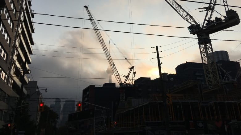 A silhouette of a crane at a construction site.