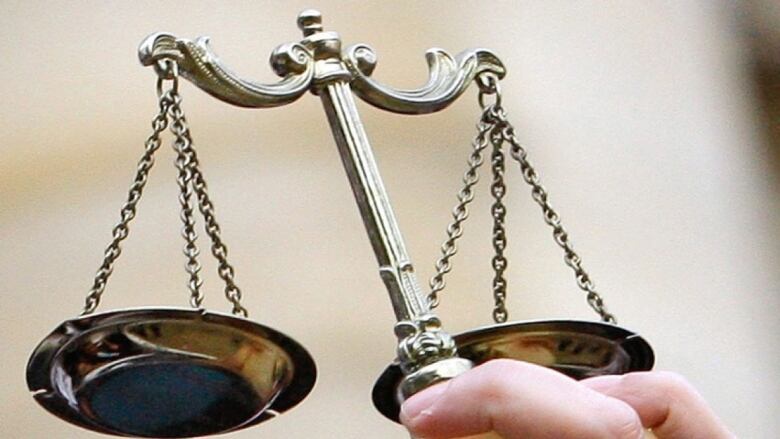 A close-up image of the scales of justice being held in someone's hand.