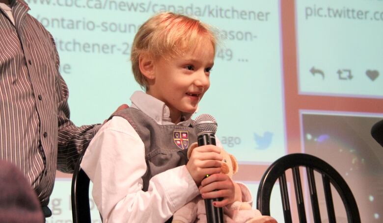 A young girl holds a CBC microphone and speaks during an interview