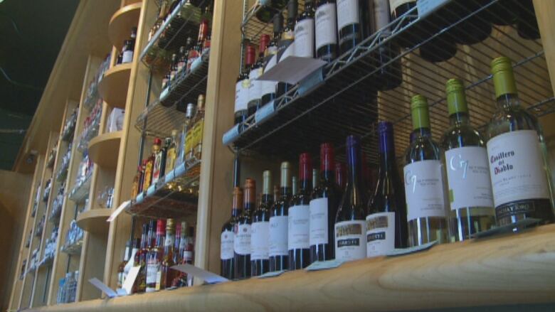 Wooden shelving unit containing rows of different kinds of alcohol.