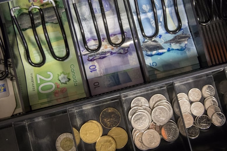 A closeup of a cash register drawer shows rows of bills and coins.