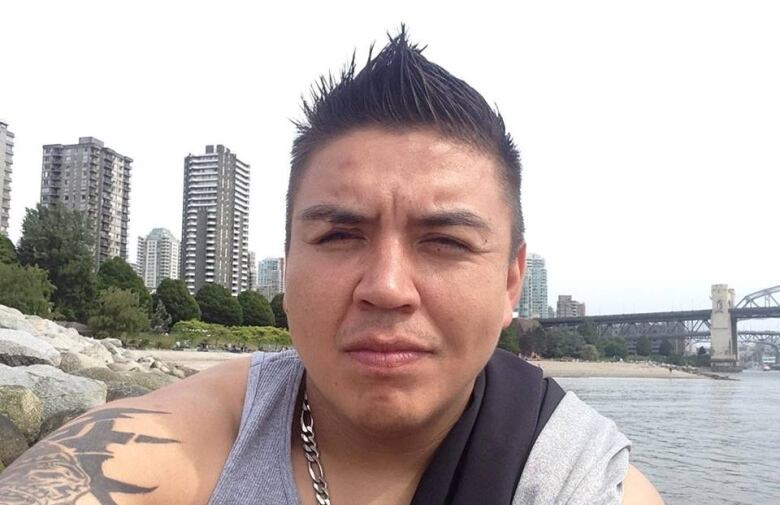 Portrait of a man with black, spiked hair on a beach.