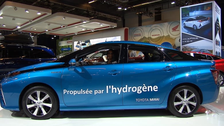 A blue vehicle with French lettering sits in an auto show.