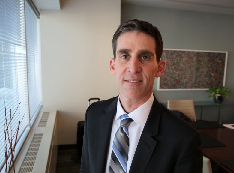 A man wearing a suit stands in an office.