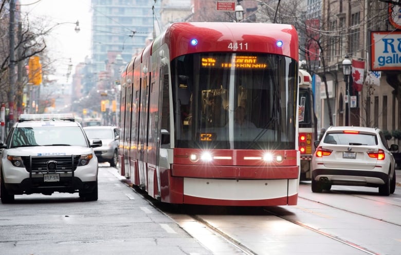 A red streetcar driving on the street.