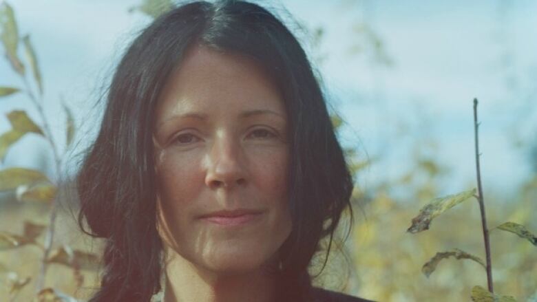 A woman with black hair smiles into the camera.