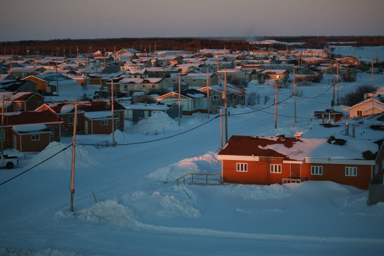 Single story homes nestled in snow in evening light