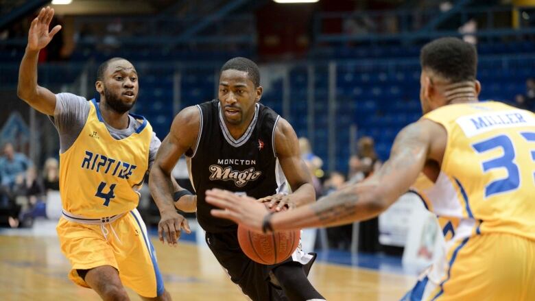 A Moncton Magic player dribbles between two Saint John Riptide players.