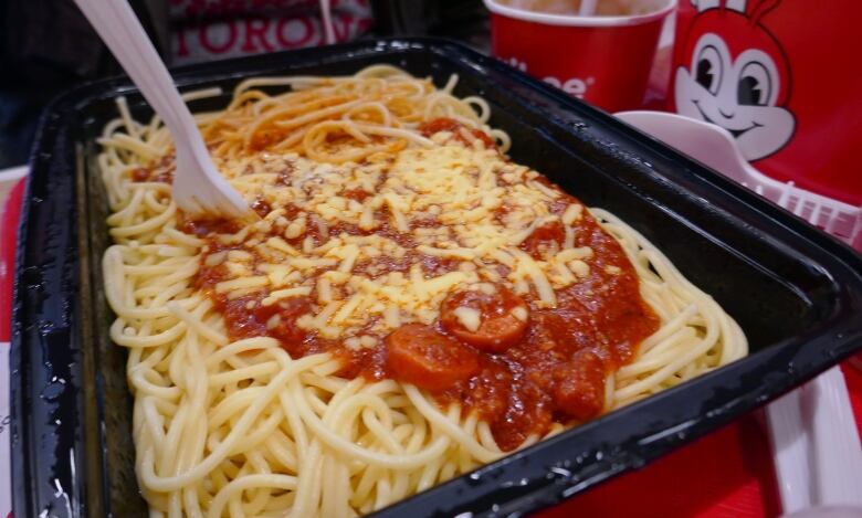 Spaghetti topped with tomato sauce, hotdog pieces and grated cheese.