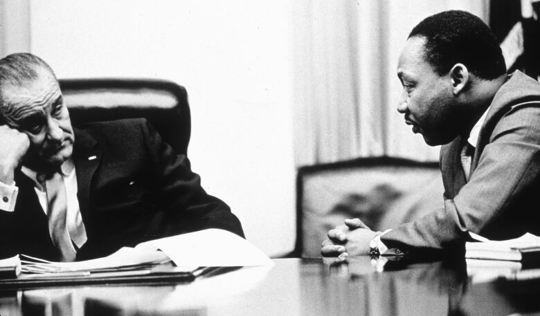 President Lyndon B Johnson (L) faces civil rights campaigner Martin Luther King Jr. across a table in this B&W images from 1965.