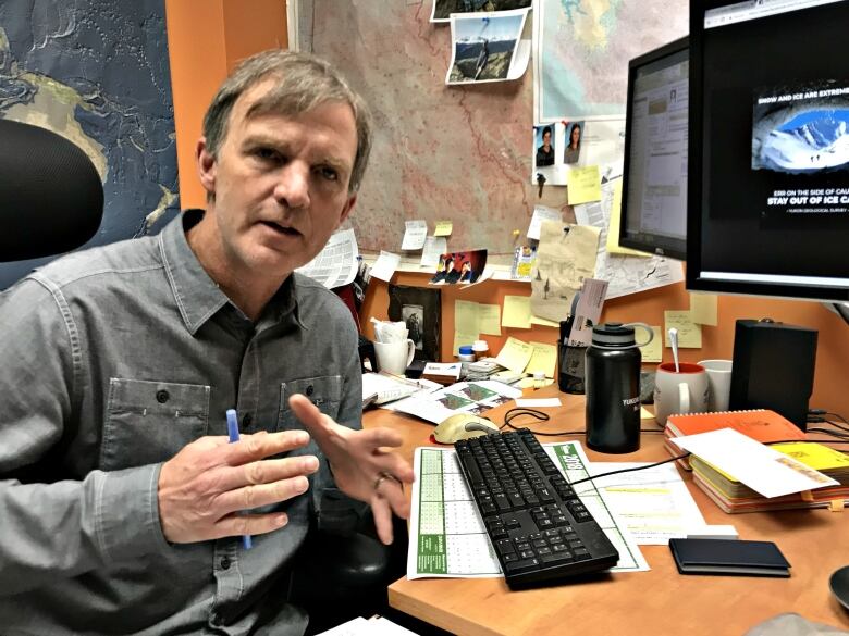 A man sits at a computer in an office.