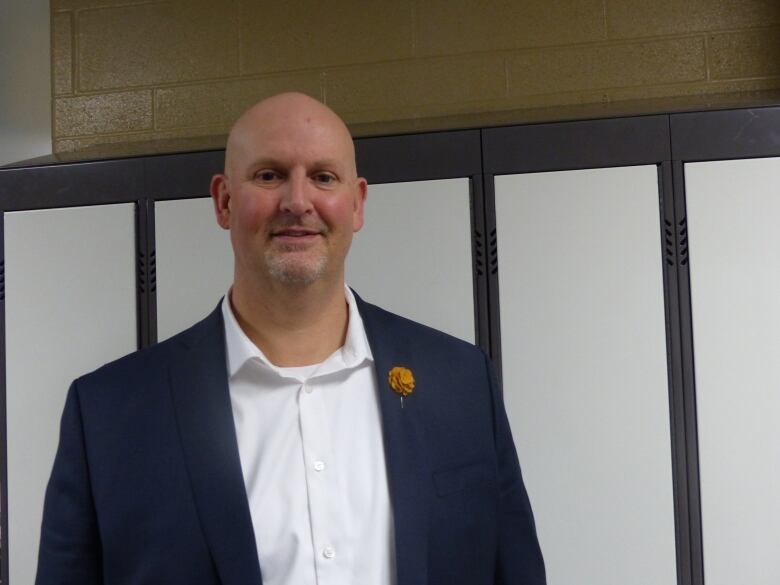 A man wearing a suit in front of a row of lockers