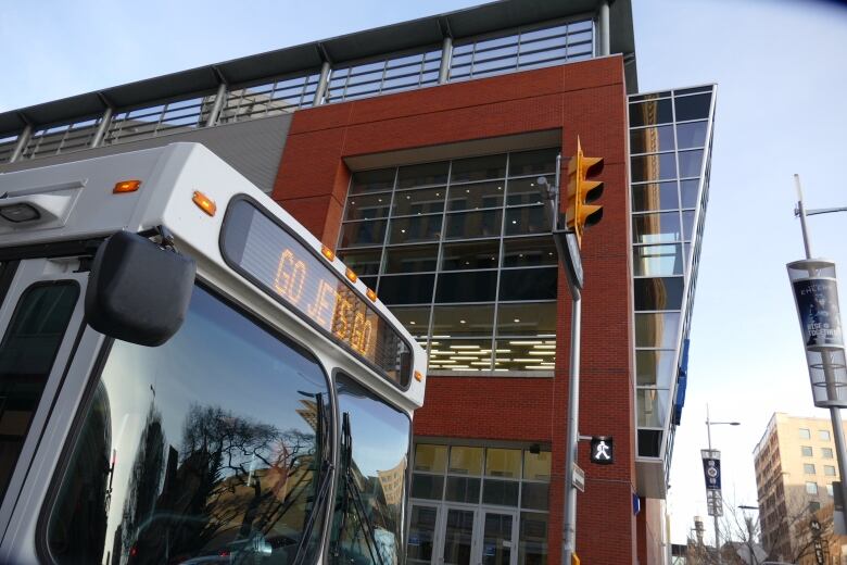 The digital sign on the front of a bus driving down a city street reads 