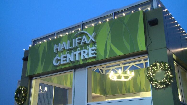 An outdoor sign reading Halifax Shopping Centre in white on a green background at one of the mall entrances.