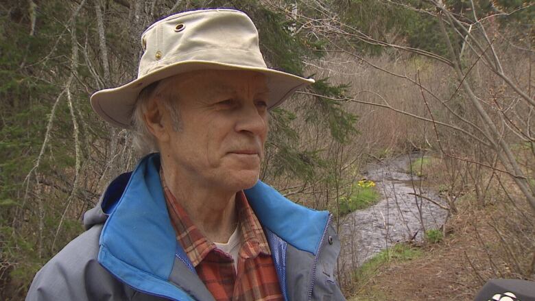 A man with a hat and coat outdoors.