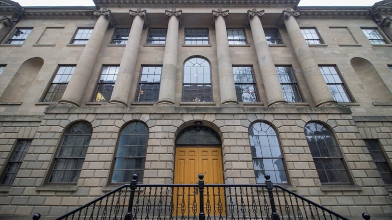 A brick building with columns and arched windows and a yellow door.