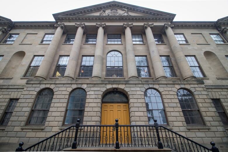 A brick building with columns and arched windows and a yellow door.