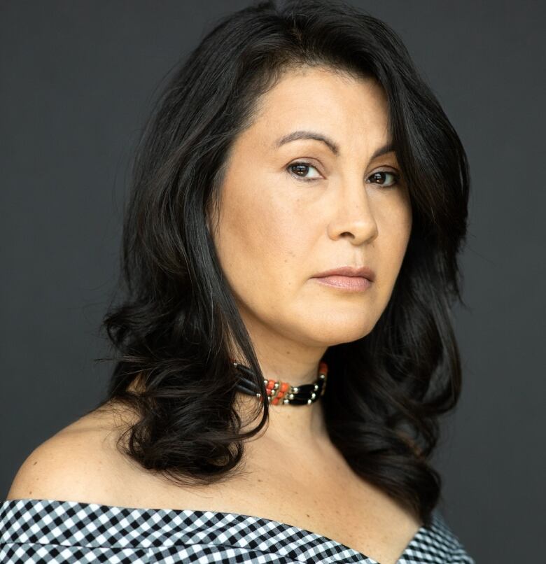 Portrait of a woman with dark hair and a beaded choker.