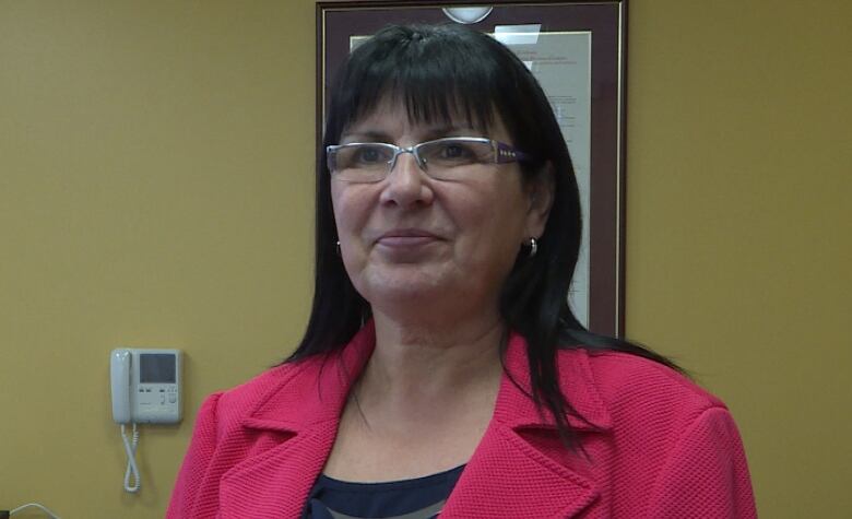 A smiling woman wearing a pink blazer.