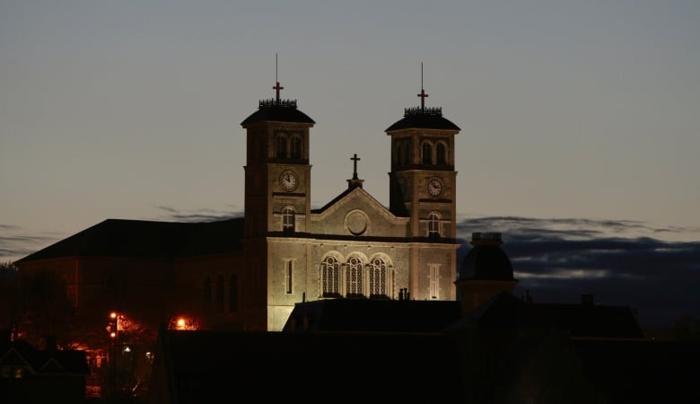 A night time view of a church towering above a darkened city skyline.