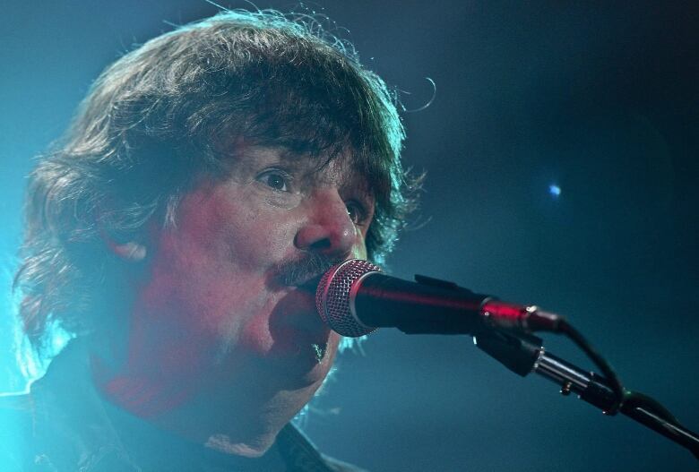 A closeup of a man singing into a microphone.