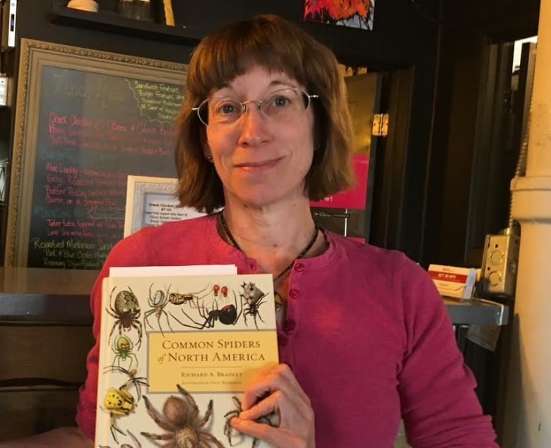 woman with bangs holding book about bugs