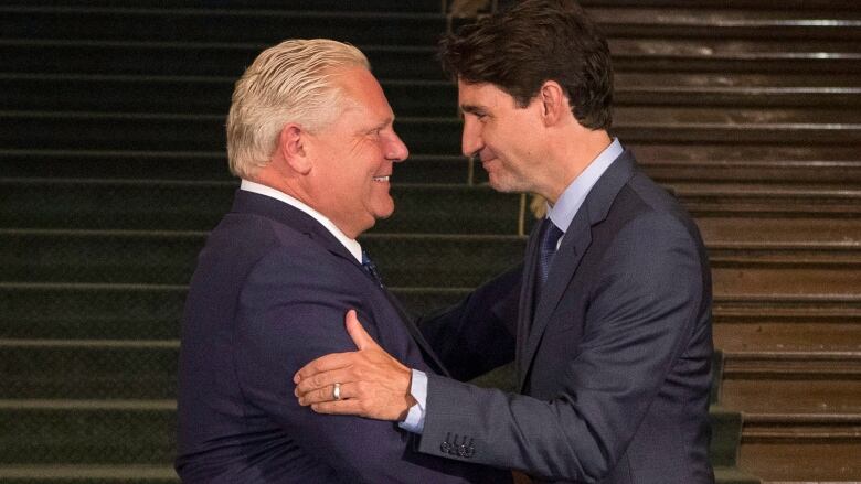 Two men in suits shake hands.