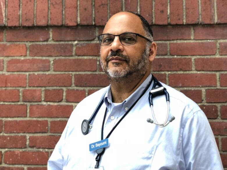 A doctor posing against a brick wall. 