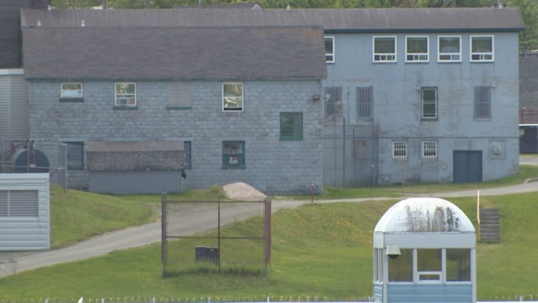 A grey prison building is pictured with a guard tower in the foreground.