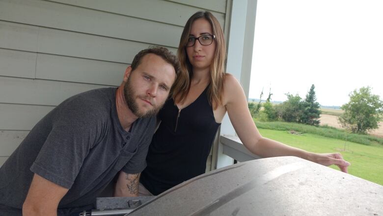 A man and woman stand on the deck of a home.