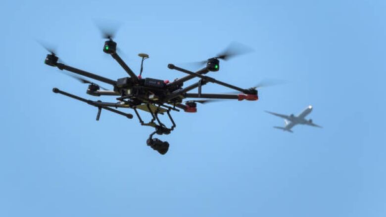 A black drone against a blue sky.