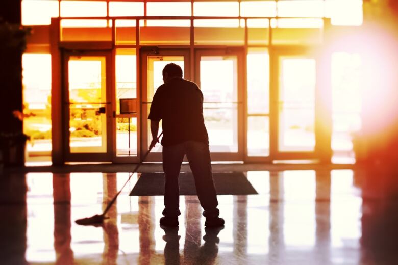 A man is shown mopping a floor.