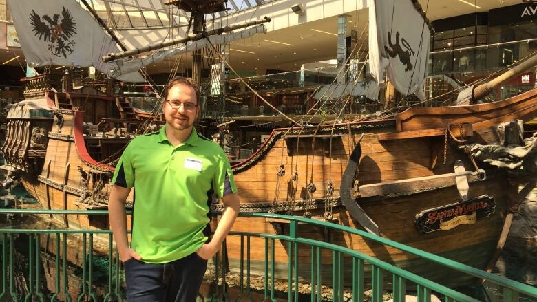 A man stands in front of a pirate ship. 