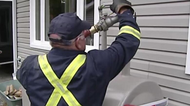 A man fills a furnace oil tank with fuel.