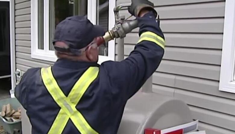 A man fills a furnace oil tank with fuel.