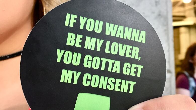 A woman holds a coaster with the words: 