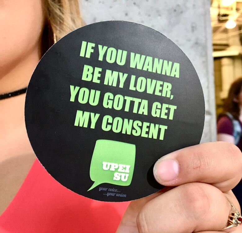 A woman holds a coaster with the words: 