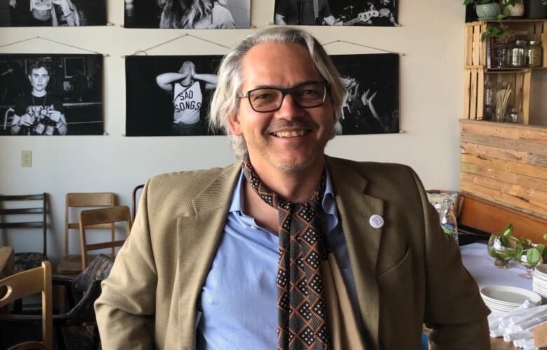 A man wearing a scarf sitting at a cafe.