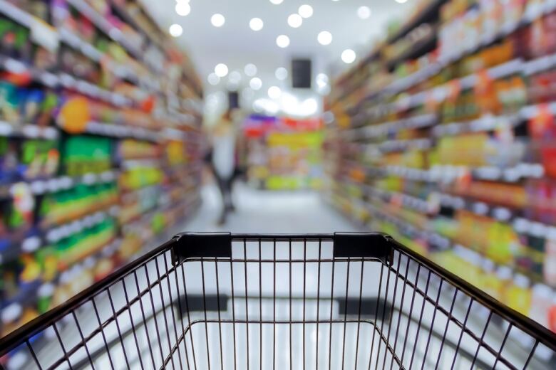 A stock image shows a shopping cart in the foreground with a grocery store aisle out of focus in the background.