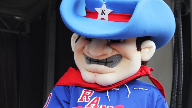 A mascot that looks like a man wearing a blue cowboy hat with a red band around it and a white star at the front