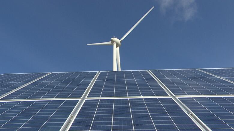 A windmill is seen above an array of solar energy panels.