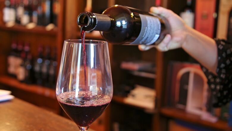 A sommelier pours a glass of red wine.