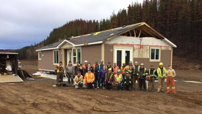 A group of workers pose in front of a one story home that will be transferred to Telegraph Creek. 