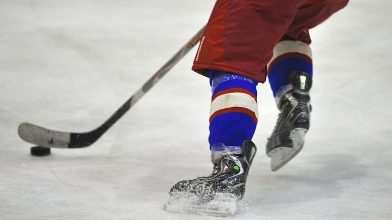 A hockey player wearing red and blue skating on an ice rink. 